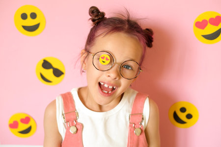 Funny comical girl in glasses with a sticker in the form of an emoji on the lens. A child surrounded...