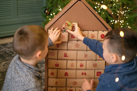 On a December morning, children check the gift compartments in the Advent calendar. The brothers are waiting for the new year.の写真素材