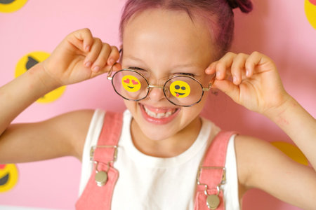 Funny Humorous laughing girl with smiley icons pasted on glasses. World Social Media Day. The problem of children's involvement in cyberspace.の写真素材