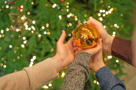 Christmas tree ball toy in the hands of children and parents. The atmosphere of New Year's mood