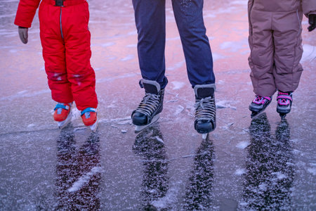 Children skate at an ice rink with an instructor. Close-up of sports shoes for skating.の写真素材