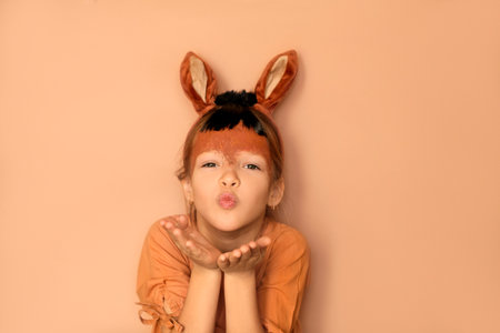 A girl in the guise of a fiery horse with a painted face blows a kiss. The symbol of the new year 2026 according to the Eastern calendarの写真素材