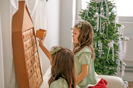 The girls open the festive Advent calendar box with a surprise. The countdown to the new year.の写真素材