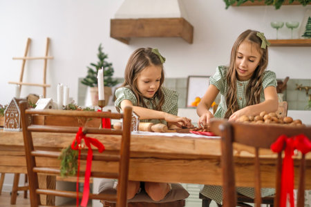Children prepare festive gingerbread cookies at the kitchen table, decorated for Christmas and New year.の写真素材