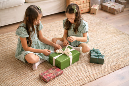 Children are untying a bow on a large Christmas box. Festive surprises for the new yearの写真素材