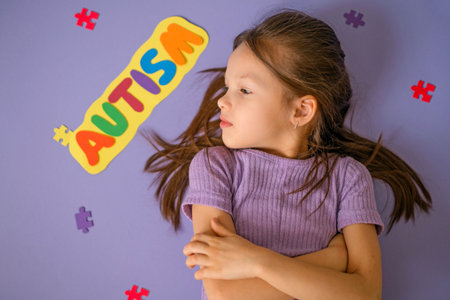 A thoughtful lonely child looks away resentfully. The inscription autism on a background decorated...