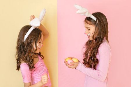 A girl gives Easter eggs to her playful, cheerful sister, rejoicing at the holiday.