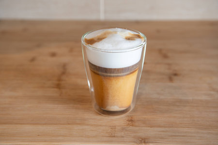 multilayer coffee or cappuccino in a glass cup on wooden tableの写真素材