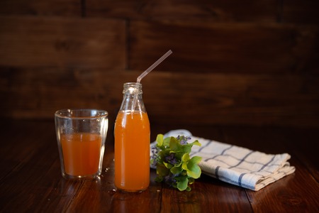 vintage bottle with juice, straw, flowers and towel on wooden tableの写真素材