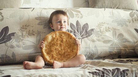 boy with uzbek cake on the couch at homeの写真素材