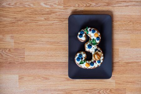 family celebration with a cake in the form of number three. Top view