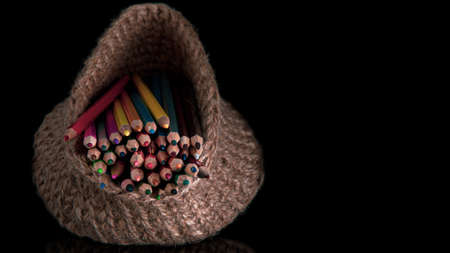 colored pencils in a knitted basket on a black background