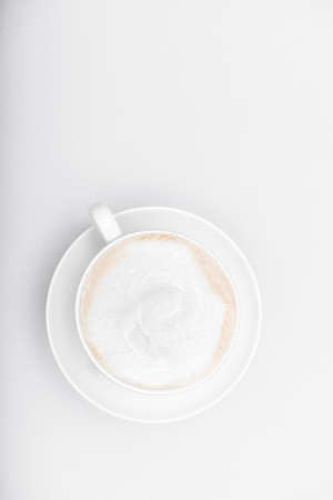 white cup with cappuccino on a white background with a place for textの写真素材