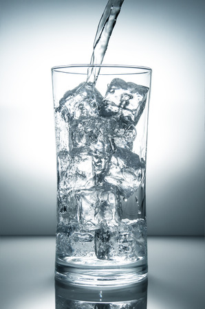 fresh water flowing in a glass with iceの写真素材