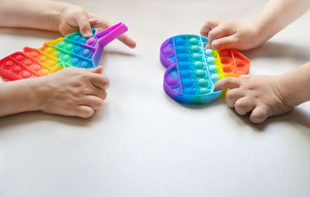 Two children playing pop it fidget. Push pop pop Bubble Sensory Fidget Toys,Stress Sensory Squeeze Toys for Children Adult Stress Relief and Anti-Anxiety Tools Squishy Toysの写真素材