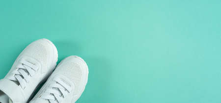 Children's sneakers on mint background. white shoes. copyspace. Banner.