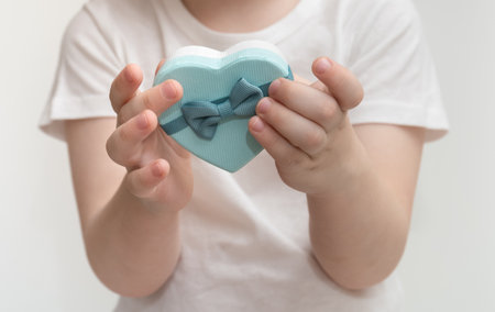 Child holds in his hands heart shaped gift box. Mothers Dayの写真素材