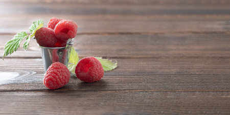 small bucket with fresh raspberries on a wooden table. copy spaceの写真素材