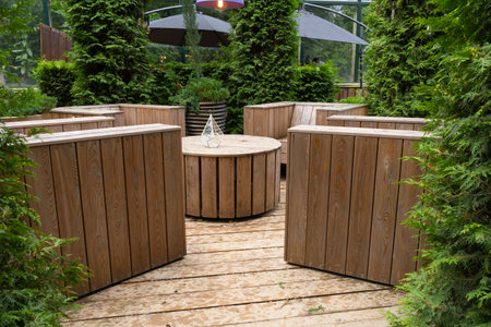 Empty cafe. Nice pot plants around the tables. Wooden table and chairs. Outdoor relaxing area