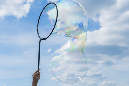 Big soap bubble. Colorful soap bubble on the blue sky. Woman create soap bubbleの写真素材