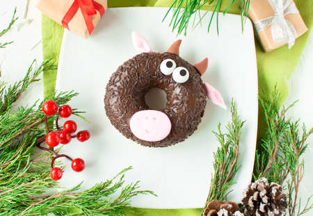 Funny donut with the symbol of the new year - a bull. New year's, xmas fun food for kids party or for breakfast. Christmas concept 2021. Beautiful and delicious cakes themed treatの写真素材