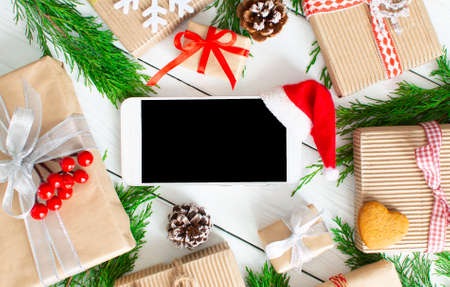 Shopping online christmas flatly. Screen of smartphone with copy space, with santa hat for app presentation and rustic decorations. Purchase presents, prepare to xmas, gift boxes. Winter holidays salesの写真素材