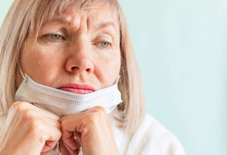 Portrait of a sad woman wearing a medical mask due to the coronavirus epidemic. Sadly looks away....