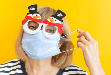 Senior woman wearing protective mask and New Year's glasses on isolated yellow background. Quarantine. Stay at home. Helter in place. Coronavirus quarantineの写真素材