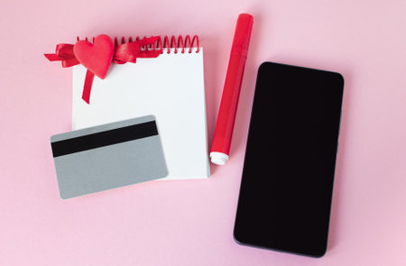 Valentine Day online Shopping. Credit card, smartphone, notepad, red heart. Seasonal Holiday sale. Romantic planning shopping for wedding, women's day, buying gifts Valentine's Day for lovers.の写真素材