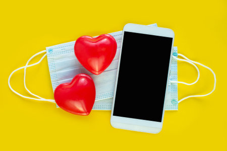 Valentines Day smartphone, Medical mask and red hearts. Covid-19 Valentine. Coronavirus Valentine. New normal COVID 19. Online communication, virtual love, loneliness web Internet.の写真素材