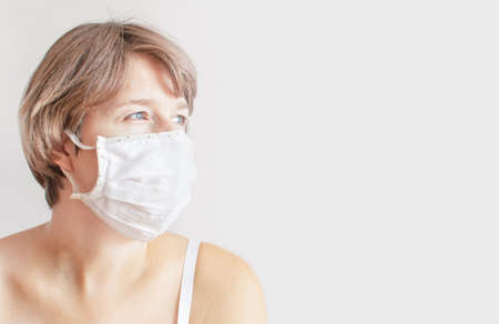 Sad woman medical mask due to the  epidemic. Sadly looks away. Concept of frustration,  pandemic, fatigue, anxiety, old age and illness, health. Copyspaceの写真素材