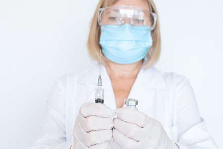 Adult doctor, nurse, infectious disease scientist hand in white protective gloves holds the flu, measles, vaccination, prepares for vaccination.の写真素材