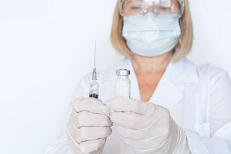 Adult doctor, nurse, infectious disease scientist hand in white protective gloves holds the flu, measles, vaccination, prepares for vaccination. Medicine and conceptの写真素材