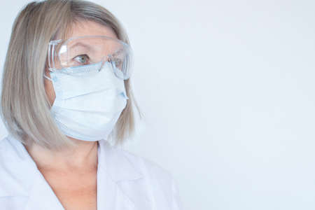 Adult doctor, nurse, infectious in goggles and medical mask disease scientist holds the flu, measles, vaccination, prepares for vaccination. Medicine and drugs conceptの写真素材
