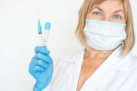 Adult doctor, nurse, infectious disease scientist hand in blue protective gloves holds the flu, measles, vaccination, prepares for vaccination. Medicine and conceptの写真素材