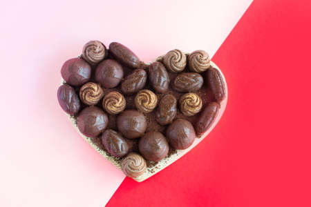 Heart shaped box with chocolates on a red-pink background. Flat lay. Valentine's day, love, giftsの写真素材