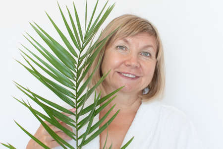 Senior woman smiling Anti-aging concept with palm leaf. Mature woma face after spa treatment. Old age in joy, plastic surgery clinic, cutie grandmother, cosmetology, new seniorの写真素材