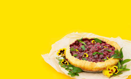 Spring cherry pie, decorated with edible flowers on a yellow background. Hello summer. Concept baking, cookbook recipes, bakery banner, cafe advertisement. Vacation sales spring, summer and holiday.の写真素材