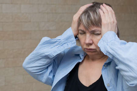 Senior woman addict and alcoholism alone depression stress sitting on the floor with her head in her hands. Headache, dizziness, migraine, violence, migraine, psychological health, emotional anxietyの写真素材
