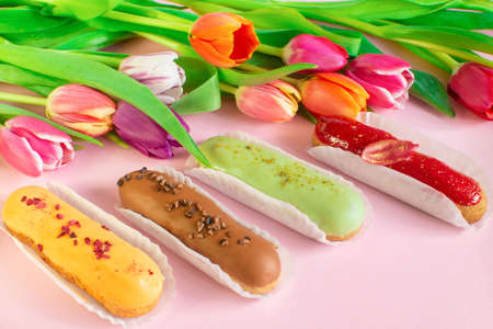 Delightful eclairs and vibrant tulips and muscari flowers. Still life Hello summer mood. Concept baking, cookbook recipes, bakery banner, cafe advertisement. Vacation sales summer and holiday.の写真素材
