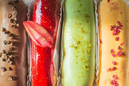 Eclairs chocolate, raspberry, pistachio and lemon close-up. Hello sweet mood. Concept baking, cookbook recipes, bakery banner, cafe advertisement. Background for vacation sales summer and holiday.の写真素材