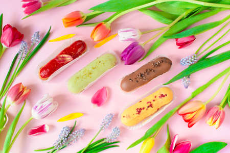 Delightful eclairs and vibrant tulips and muscari flowers. Still life Hello summer mood. Concept baking, cookbook recipes, bakery banner, cafe advertisement. Vacation sales summer and holiday.の写真素材