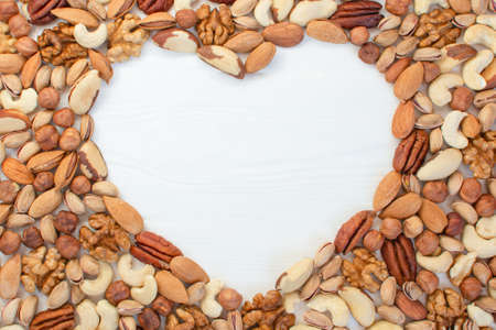 Organic mixed nuts banner with place for text in the shape of heart. Assorted nuts hazelnuts walnuts, brazilian nuts, pecans, pistachio, almonds, cashews. Healthy useful microelements. Healthy Conceptの写真素材