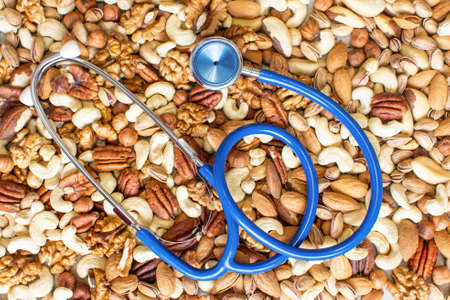 Nuts and stethoscope background. Healthy food for the heart, useful microelements and vitamins in nuts. Healthy food for the heart, useful microelements and vitamins. Healthy diet conceptの写真素材