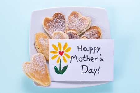 Mothers day card. Breakfast heart shaped pancakes postcard made by the kids for mom. Text Happy Mothers day. On a colored background.の写真素材
