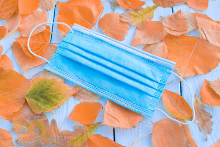 Medical mask autumn on a background of autumn leaves.の写真素材