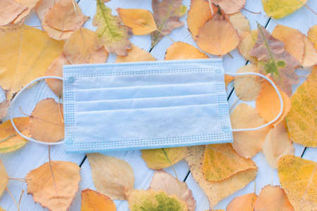 Medical mask autumn on a background of autumn leaves. Concept covid, respiratory disease, protectionの写真素材