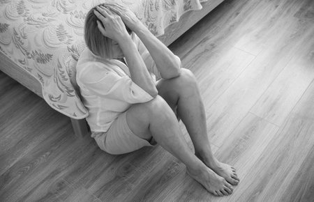 Senior woman addict and alcoholism alone depression stress sitting on the floor with her head in her...