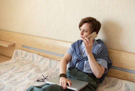 Happy woman works with mobile phone at home. Smiling young female working in cozy remote work, E...