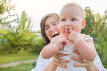 Smiling mom and little blonde daughter have fun outdoors in the garden outdoors. Active leisure of a...